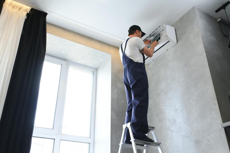 Smiling young male electrician repair conditioner in client home