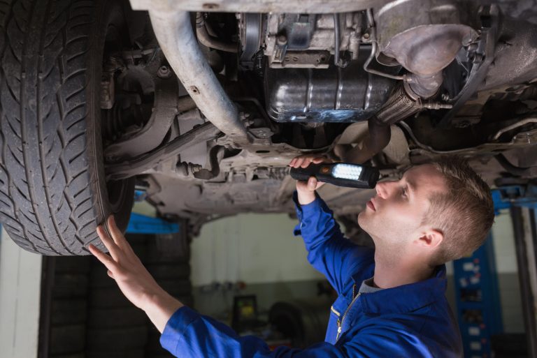 Male,Mechanic,Examining,Car,Using,Flashlight